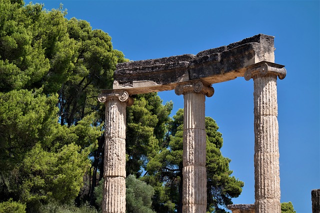A view of an old greek temple with trees in the background.