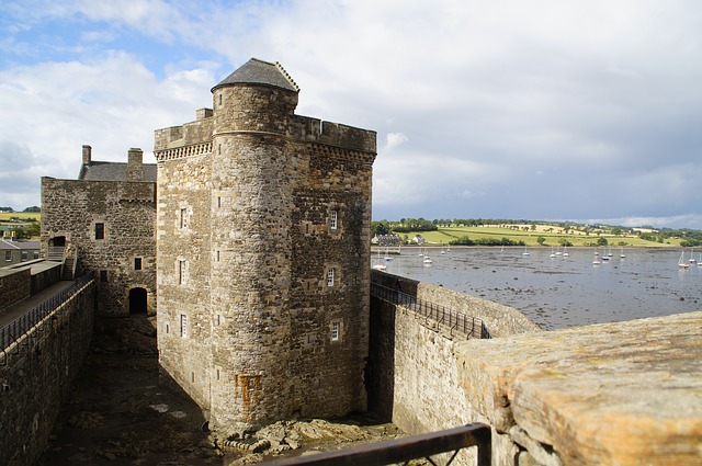 A stone wall with a tower and a bridge in the background.