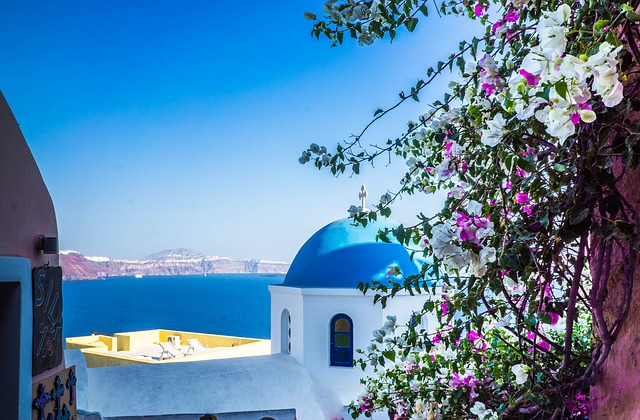 A white building with blue domes and flowers in the foreground.