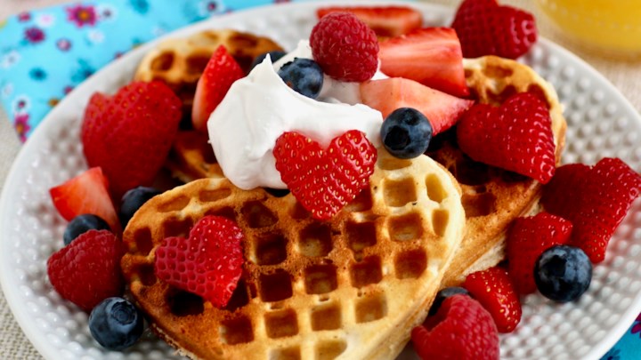 A plate of waffles with strawberries and blueberries.