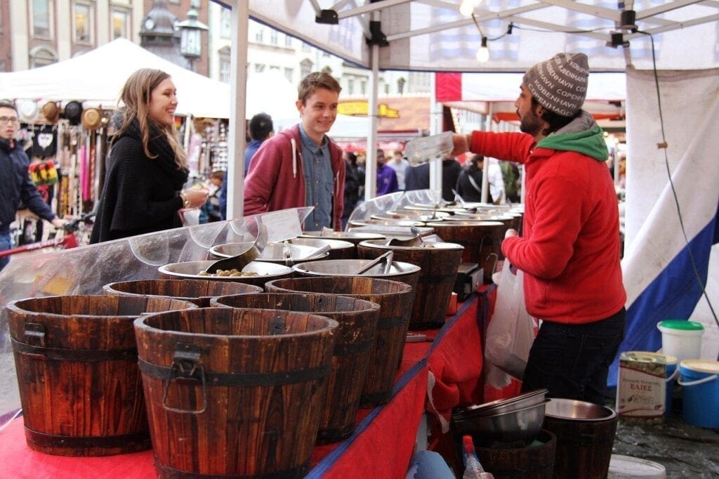 A group of people standing around some wooden buckets.