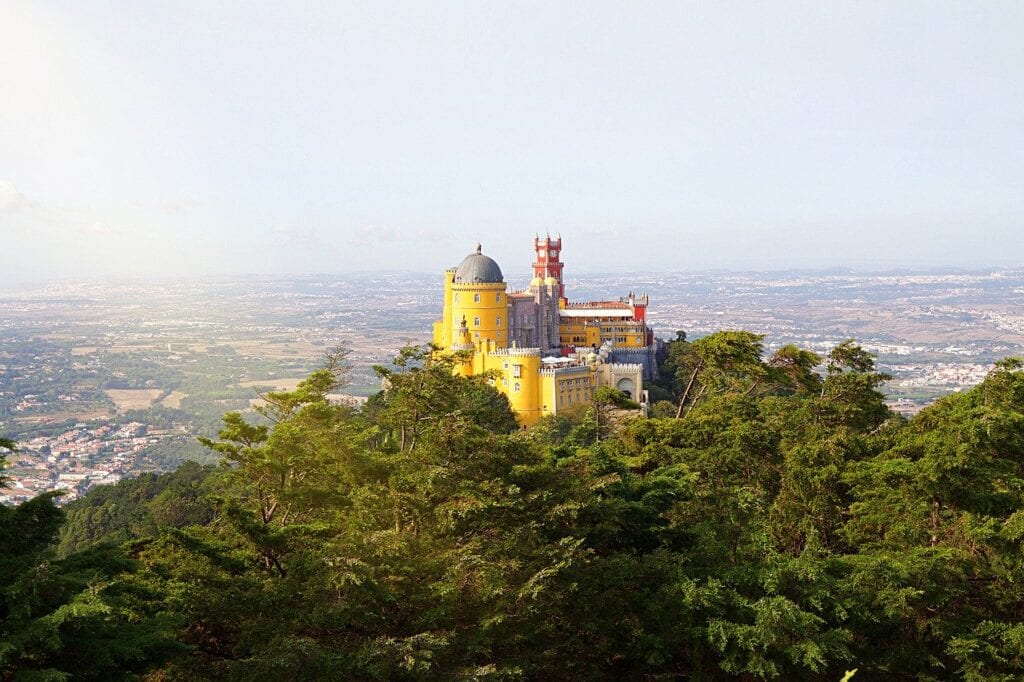 A yellow castle sits on top of a hill.