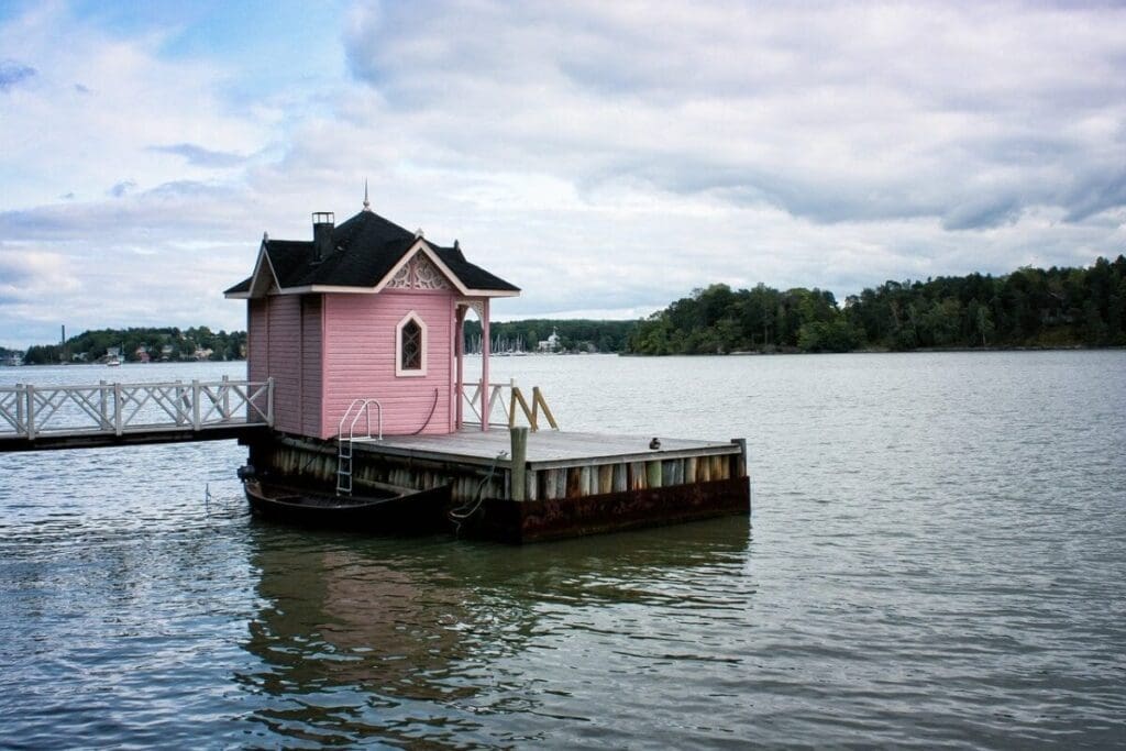 A pink house sitting on top of a dock.