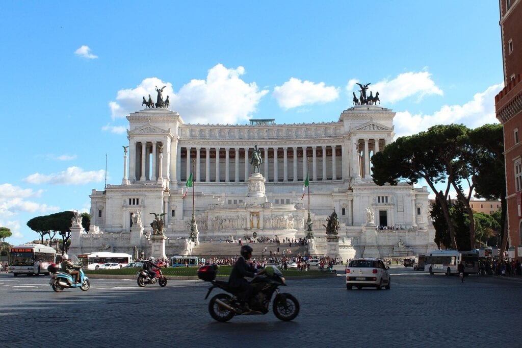 A motorcycle rider in front of the monument to victor emmanuel ii.