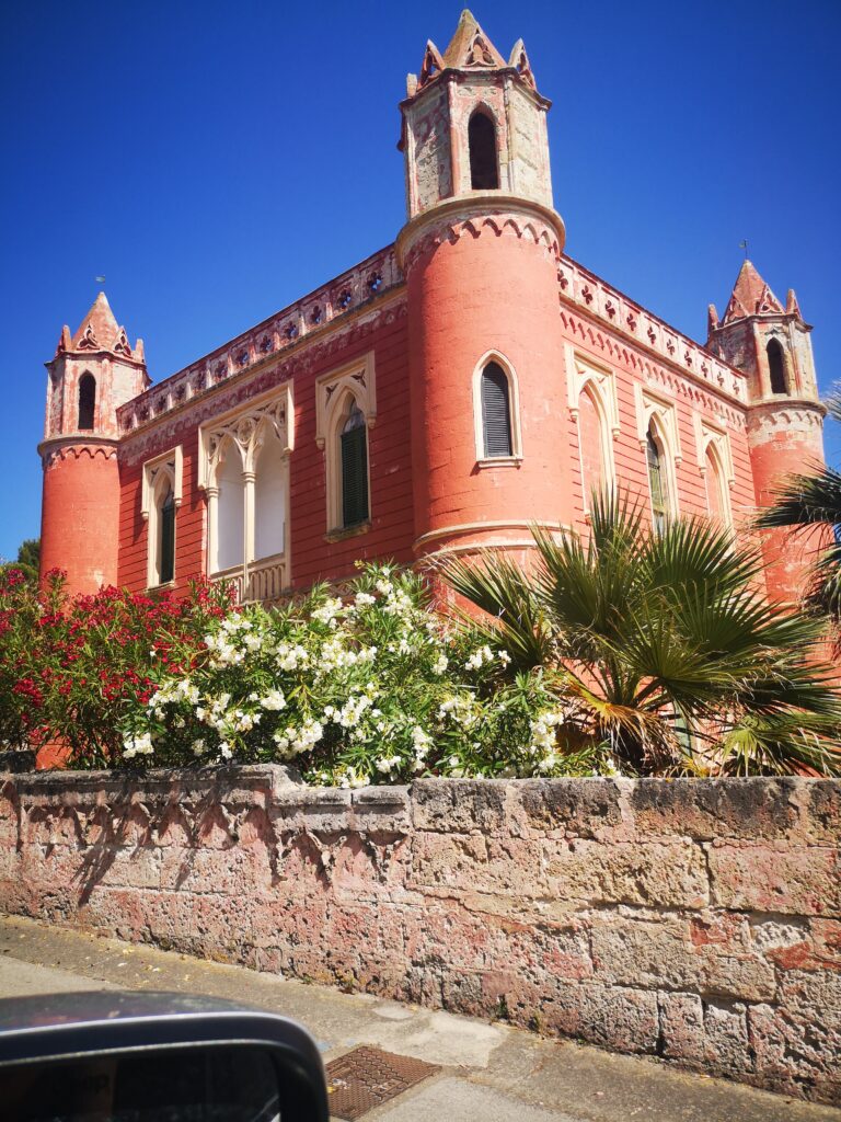 A red brick building with two towers and a palm tree.