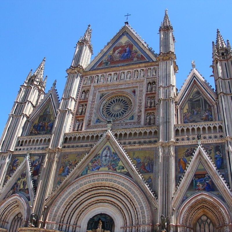 A cathedral with many windows and a clock on the front.