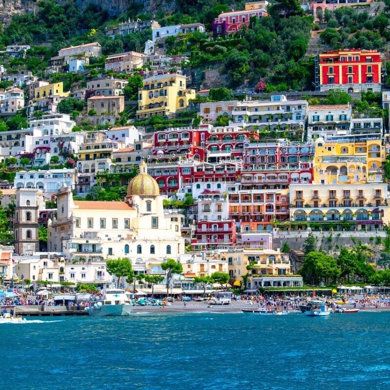 A view of the ocean and houses on top of a hill.